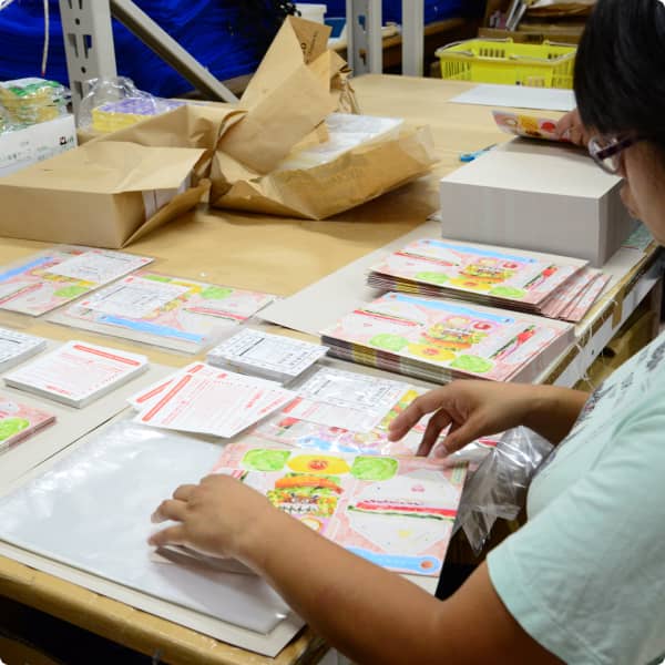 テーブルの上で丁寧にチラシやパンフレットを梱包する様子