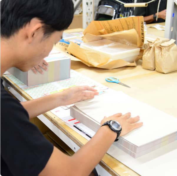 テーブルの上で印刷物の梱包作業を行う男性