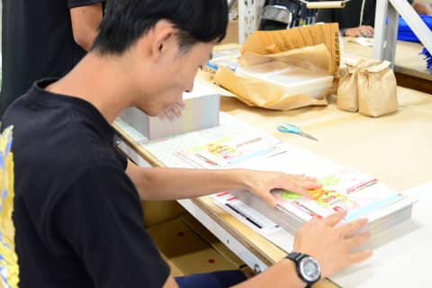 パッケージング用のチラシを揃える作業員の手元