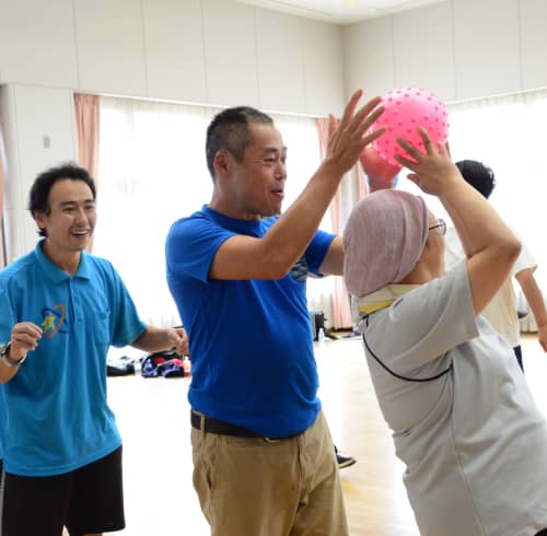 ピンクのボールを持ち上げる女性とサポートする男性たち