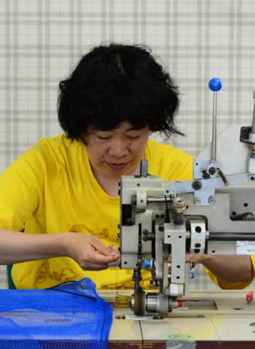 黄色いシャツを着た女性が作業台で作業中